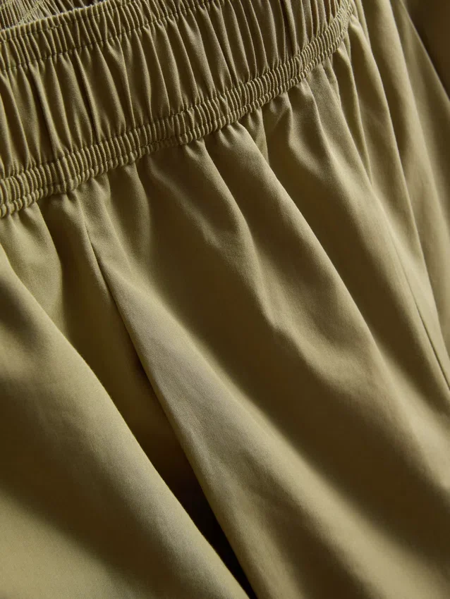 Broek met plooien en wijd uitlopende pijpen met papierachtige textuur