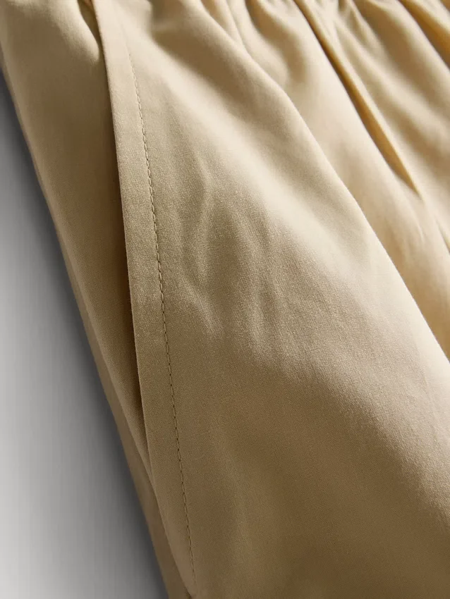 Broek met plooien en wijd uitlopende pijpen met papierachtige textuur